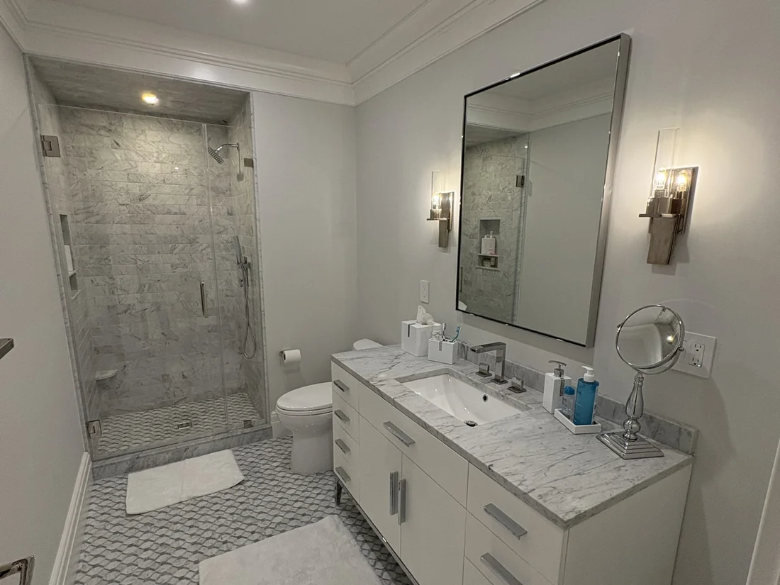 Remodeled bathroom with marble vanity walk-in shower and patterned floor tile