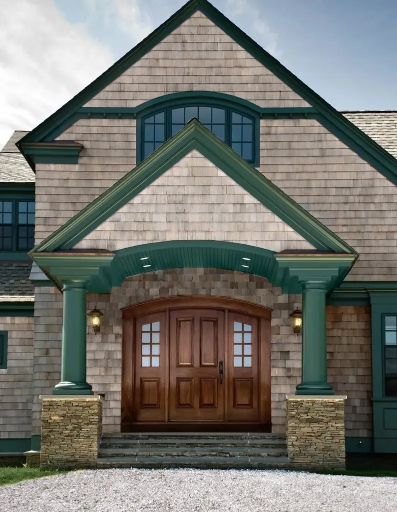 Home entrance with cedar shake siding, forest green trim and stacked-stone column bases