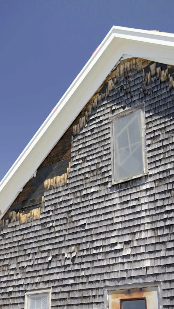 Gable end of the storage barn with cedar shingles removed and new white rake trim installed